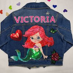 a denim jacket with the words victoria on it and a little mermaid sitting in front of her