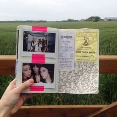 a person holding up an open book with pictures on it in front of a field