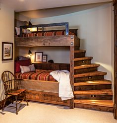 a bunk bed with steps is in the middle of a room next to a chair