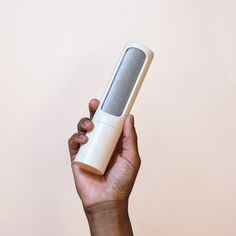 a hand holding an electronic device in front of a pink wall