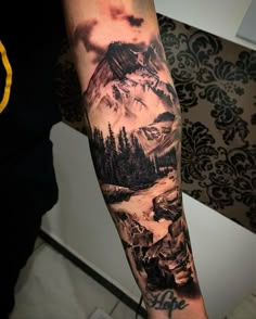 a man with a mountain landscape tattoo on his arm