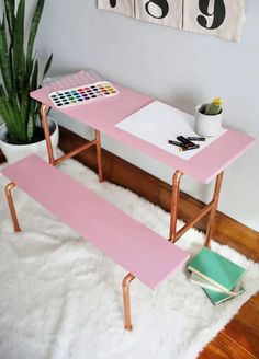 a pink table sitting on top of a white rug next to a potted plant