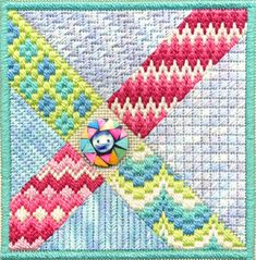 a close up of a cross stitch design on a piece of cloth with a button