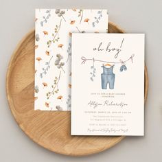 two baby shower cards sitting on top of a wooden plate