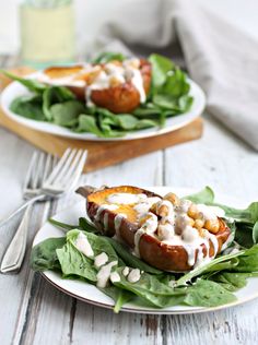 two white plates topped with food on top of a wooden table next to silverware