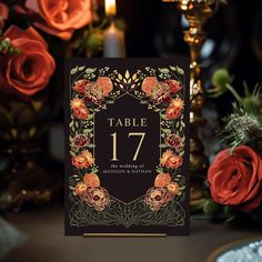 the table number is surrounded by red roses and gold foiled candles in front of it