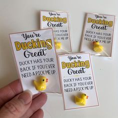 four rubber ducks are being held up by someone's hand, with the words you're ducking great on them