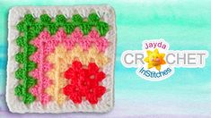 a crocheted square with flowers and leaves on the side, in front of a blue