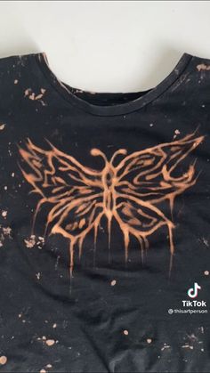 a black t - shirt with orange and brown paint splattered on it