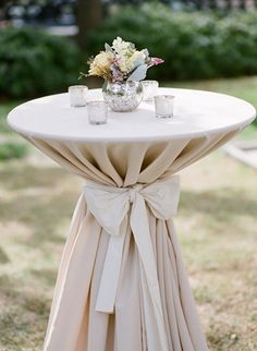 a white table topped with a vase filled with flowers next to two candles on top of it