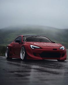 a red sports car driving down a wet road