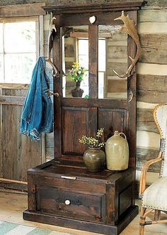 an old wooden cabinet with a mirror and coat rack on top of it next to a chair