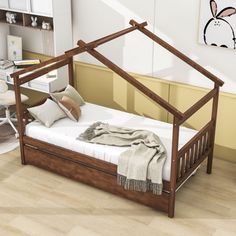 a wooden bed frame with pillows and blankets on it in a room that has stairs leading up to the second floor