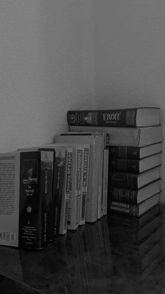 a stack of books sitting on top of a wooden table next to a white wall