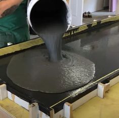 a man pouring cement into a large bucket