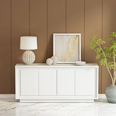 a living room with a white cabinet next to a potted plant and a painting on the wall