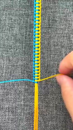 someone is stitching the end of a blue and yellow piece of fabric with scissors