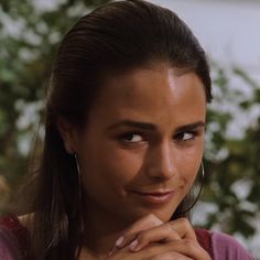 a woman with her hand on her chin looking at the camera while wearing ear rings