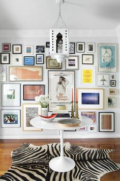 a dining room with pictures on the wall and a zebra rug in front of it