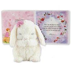 a white stuffed rabbit sitting next to a pink and purple greeting card with an image of a bunny