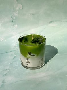 a glass filled with green liquid sitting on top of a table