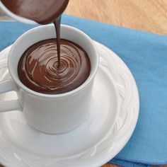 a white cup filled with chocolate on top of a saucer next to a blue napkin