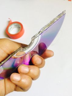 a person holding a small object in their left hand and some tape on the other