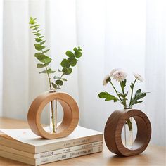 two wooden vases with flowers in them sitting on top of a stack of books