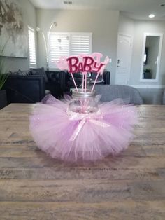 a pink tutule sitting on top of a wooden table in front of a window