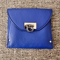 This Salvatore Ferragamo Wallet Is A Triumph Of Style And Design. Finished In Textured Bright Blue Leather, This Wallet Folds Out To Reveal Many Card Pockets And Long Pockets For Cash. This Is Secured By A Silver-Tone Twist Lock. The Back Pocket Opens To An Accordion Fold Compartment. Exterior Material Leather Interior Material Nylon Length 5” Width 0.39” Height 4” Hardware Silver Tone Modern Blue Leather Clutch, Formal Blue Bags With Card Slots, Everyday Luxury Blue Clutch, Elegant Blue Coin Purse With Card Slots, Compact Blue Bags For Daily Use, Leather Coin Purse With Magnetic Closure For Travel, Blue Leather Clutch With Removable Pouch, Blue Envelope Bag For Daily Use, Chic Blue Rectangular Wallet