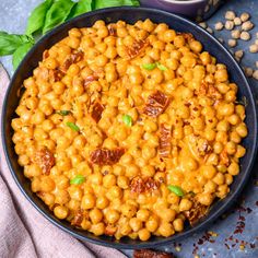 a pan filled with cooked chickpeas and garnished with green leaves on the side