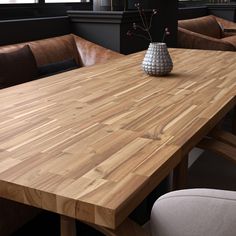 a large wooden table with two chairs and a vase on the table in front of it