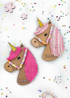 two pink and white pony brooches on top of confetti