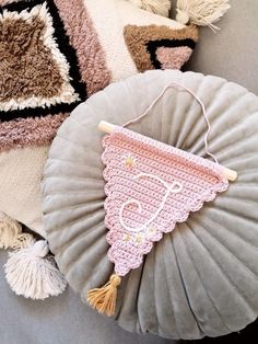 a crocheted baby blanket hanging from a pillow on a couch with tassels around it