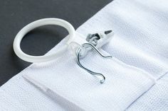 a pair of white scissors on top of a piece of cloth next to a hook