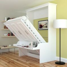 an open white storage box sitting on top of a hard wood floor next to a lamp