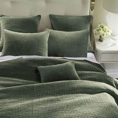 a bed with green bedspread and pillows