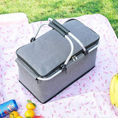 a lunch box sitting on top of a pink and white table cloth next to fruit