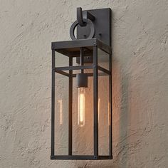 an outdoor light on the side of a building with two bulbs glowing from it's sides