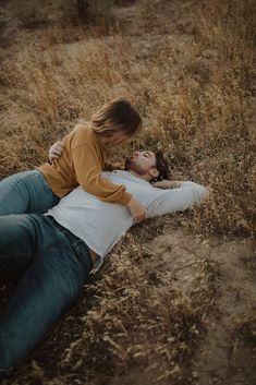 a man laying on the ground next to a woman who is holding her head down