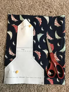 a pair of scissors sitting on top of a piece of fabric next to a cutting board