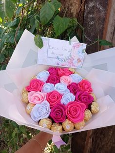 a person holding a bouquet of roses and chocolates in their hand with a note on it