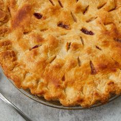 a pie sitting on top of a metal pan next to a fork and spoons