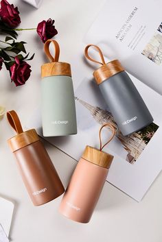 three cups with wooden handles sitting on top of a table next to flowers and papers