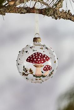 a glass ornament hanging from a tree branch with a mushroom on it's side