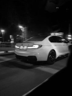 a white car driving down a street at night