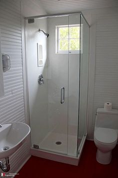 a bathroom with a sink, toilet and shower stall in the middle of the room