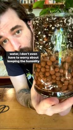 a man holding a large glass jar filled with lots of beans in it's hands