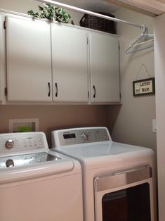 a washer and dryer in a room with white cupboards on the wall