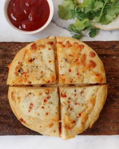 a pizza cut into four slices on a cutting board with sauce and lettuce